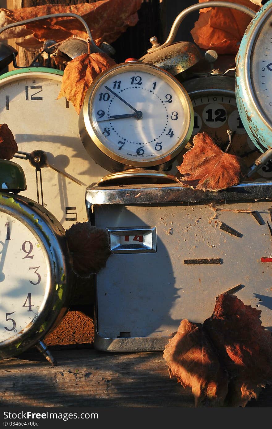 Some old timepieces with scattered amber leaves set in a rural enviroment. Some old timepieces with scattered amber leaves set in a rural enviroment