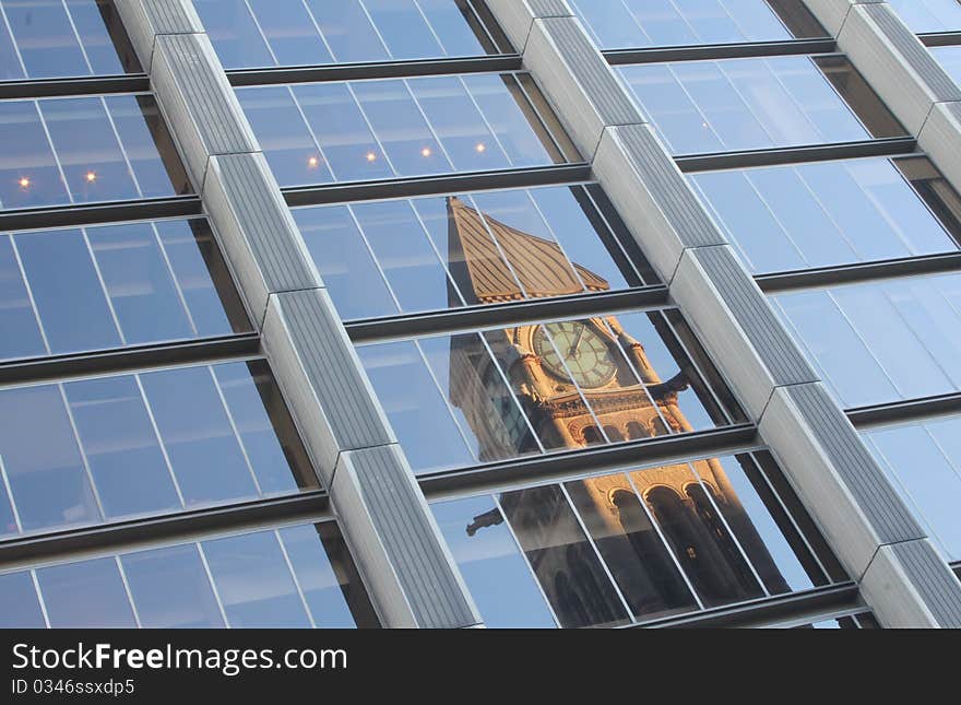 Reflection of old city hall in the windows of a modern office building