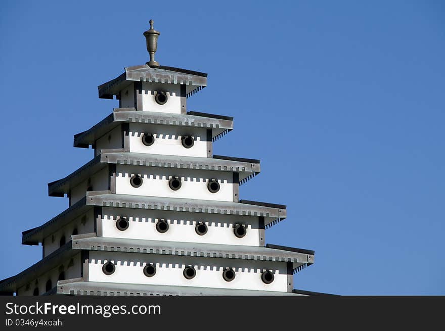 Bird house pagoda in clear blue sky.