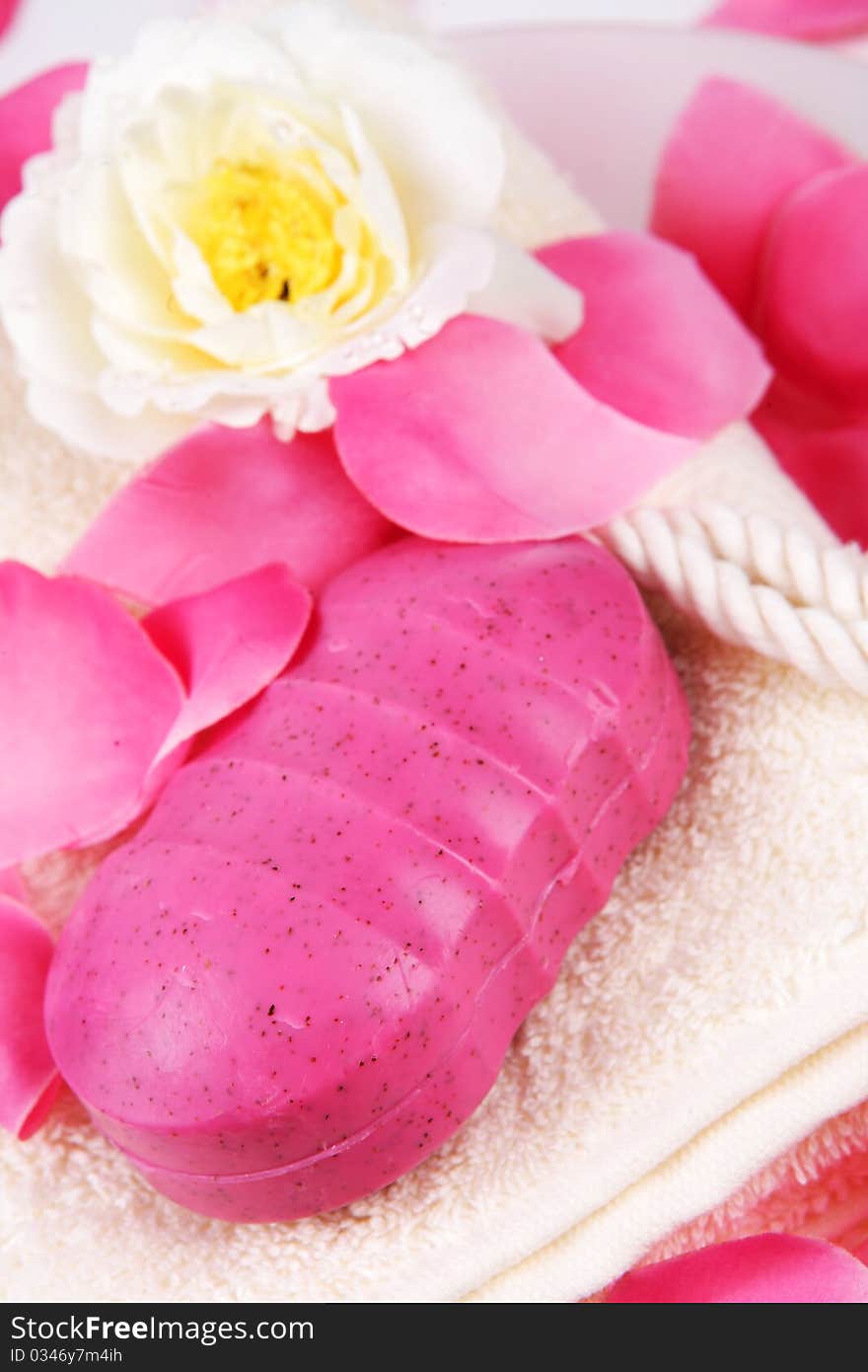 Pink hand made soap and pink rose petals on a white towel. Pink hand made soap and pink rose petals on a white towel