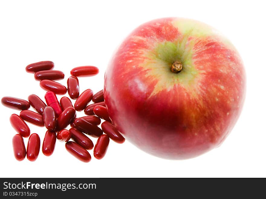 Red apple with red pills (medicines in a red cover, focus on the tablets isolated). Red apple with red pills (medicines in a red cover, focus on the tablets isolated)