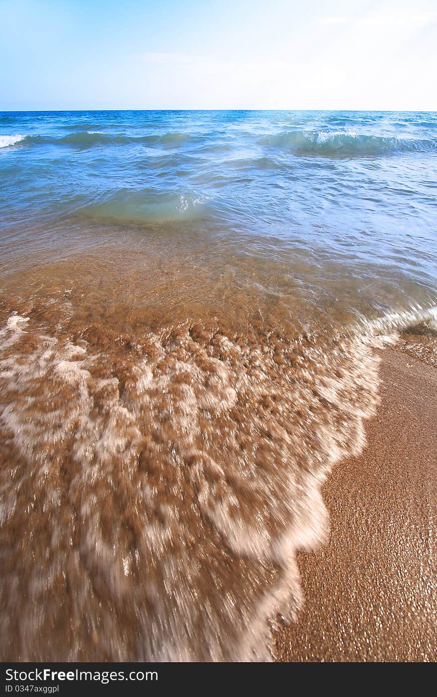 Beach pebbles under clear water with waves