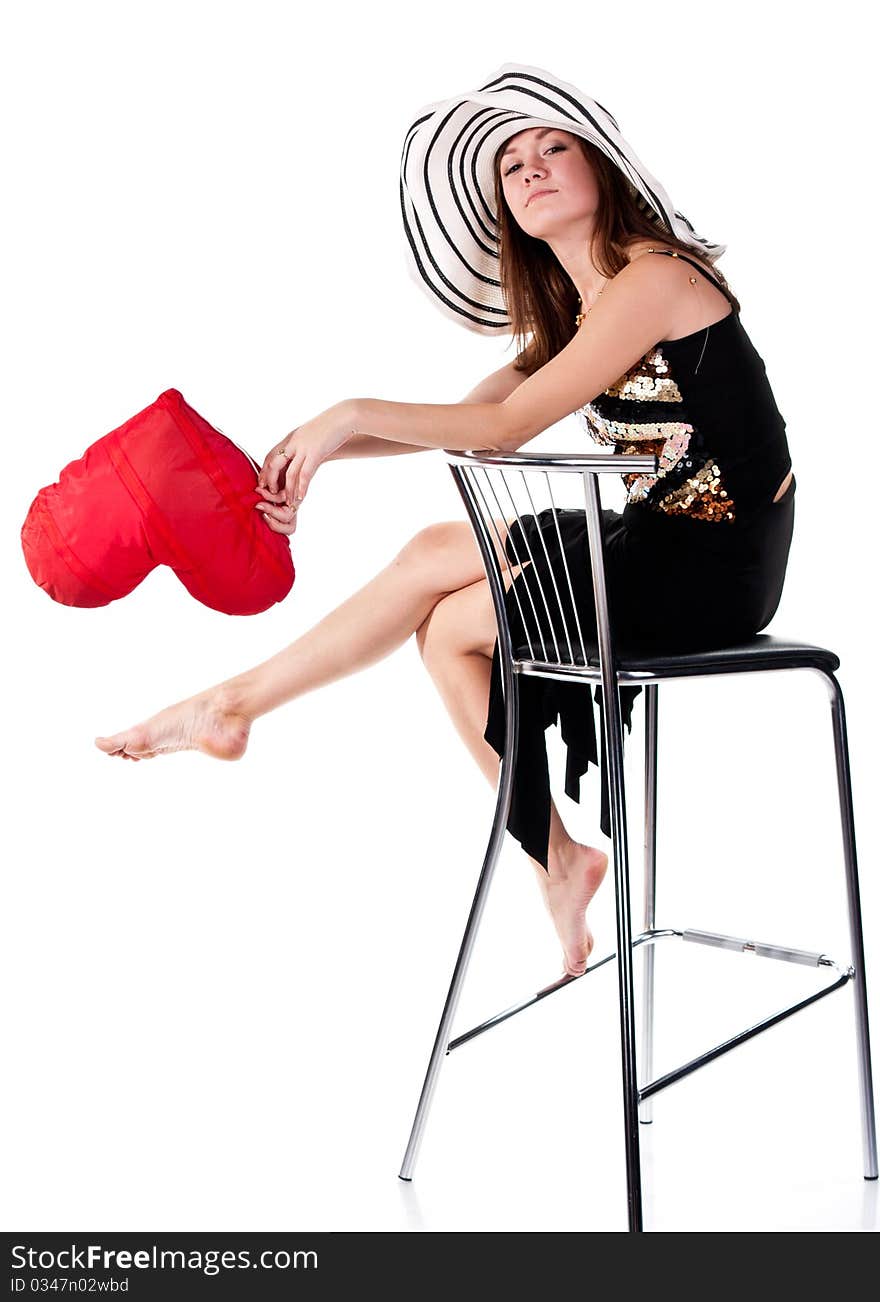 Beautiful young girl sitting on a bar chair with red heart pillow  isolated on white