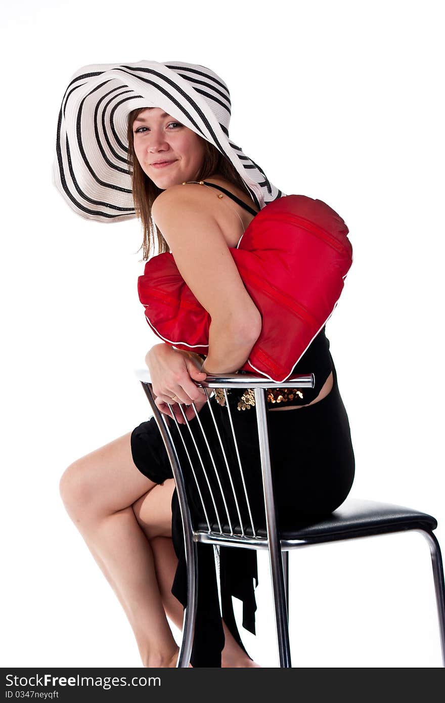 Beautiful young girl sitting on a bar chair with red heart pillow  isolated on white