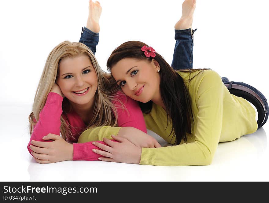 Two pretty girl friends having fun and laughing on the floor. isolated on white background