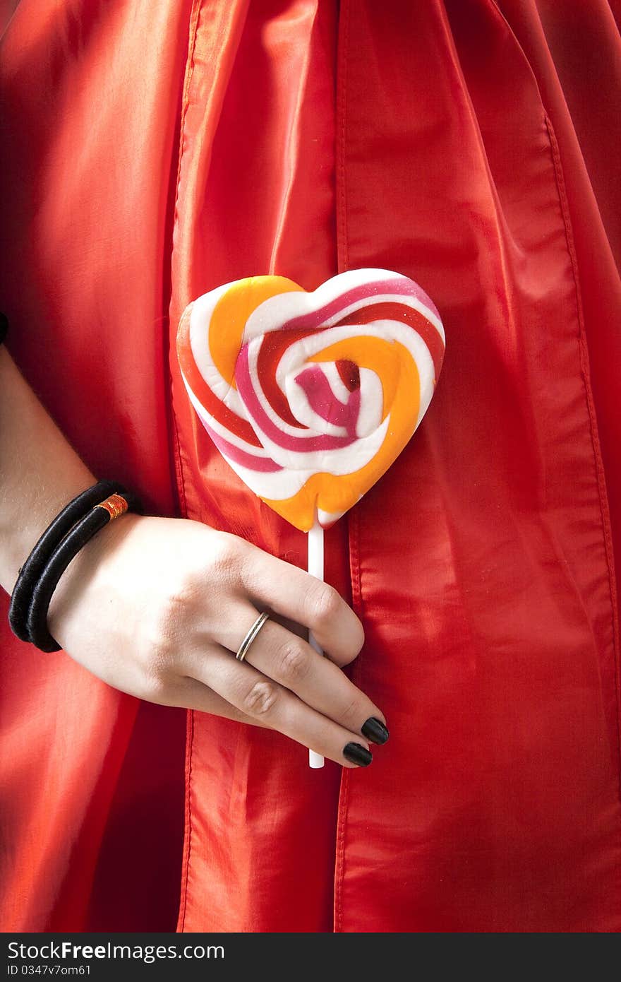 Cose up Lady's hand in a red dress holds lollipop. Cose up Lady's hand in a red dress holds lollipop