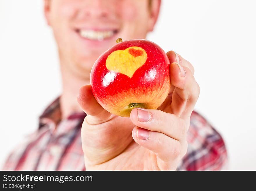 A Man is holding a red Apple with two Hearts on it. A Man is holding a red Apple with two Hearts on it