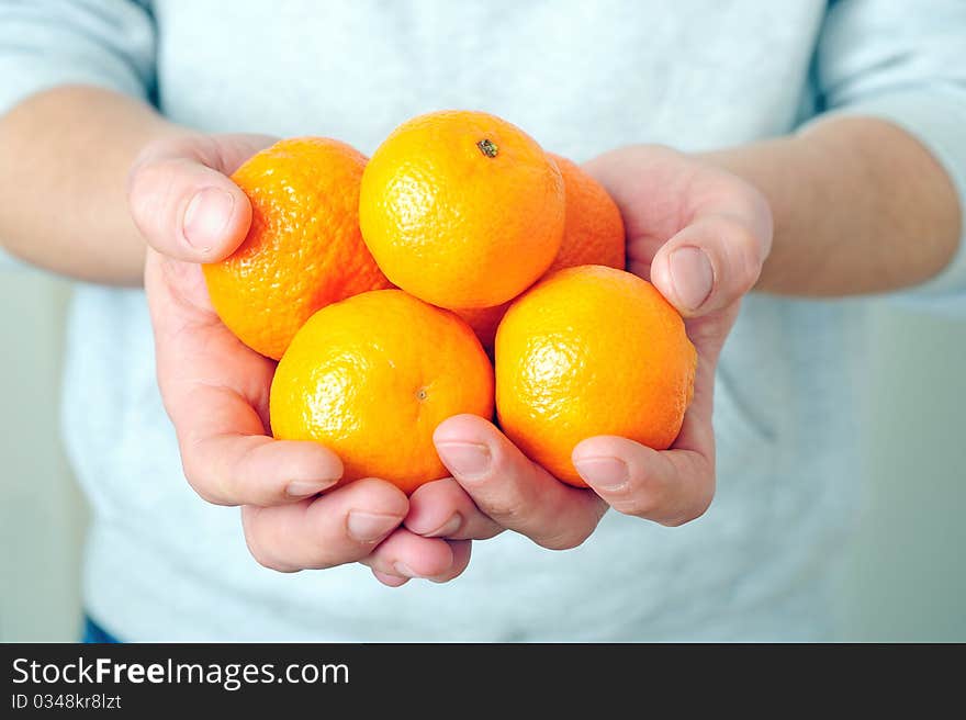 Man is holding fresh mandarins in his hands