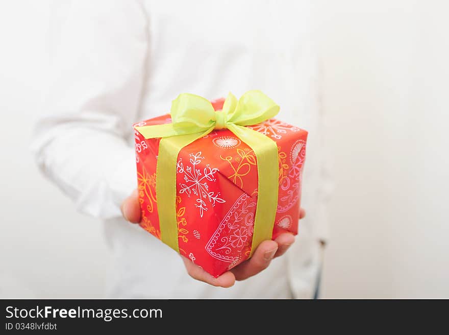 Man in a white shirt is holding a gift-box with a green ribbon. Man in a white shirt is holding a gift-box with a green ribbon