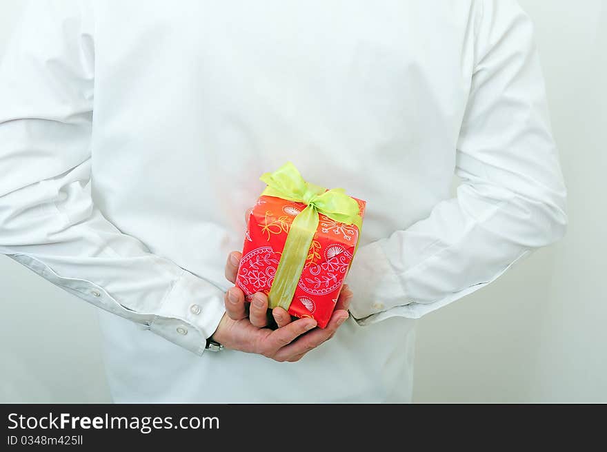 Man is holding a present behind his back. Man is holding a present behind his back