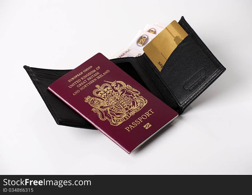 A horizontal image of bank notes sticking out of a black leather mans wallet with a passport and credit card. A horizontal image of bank notes sticking out of a black leather mans wallet with a passport and credit card