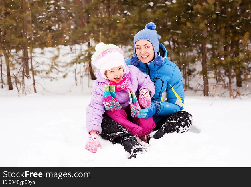 Happy family; young mother and her daughter having fun in the winter park (focus on the child). Happy family; young mother and her daughter having fun in the winter park (focus on the child)