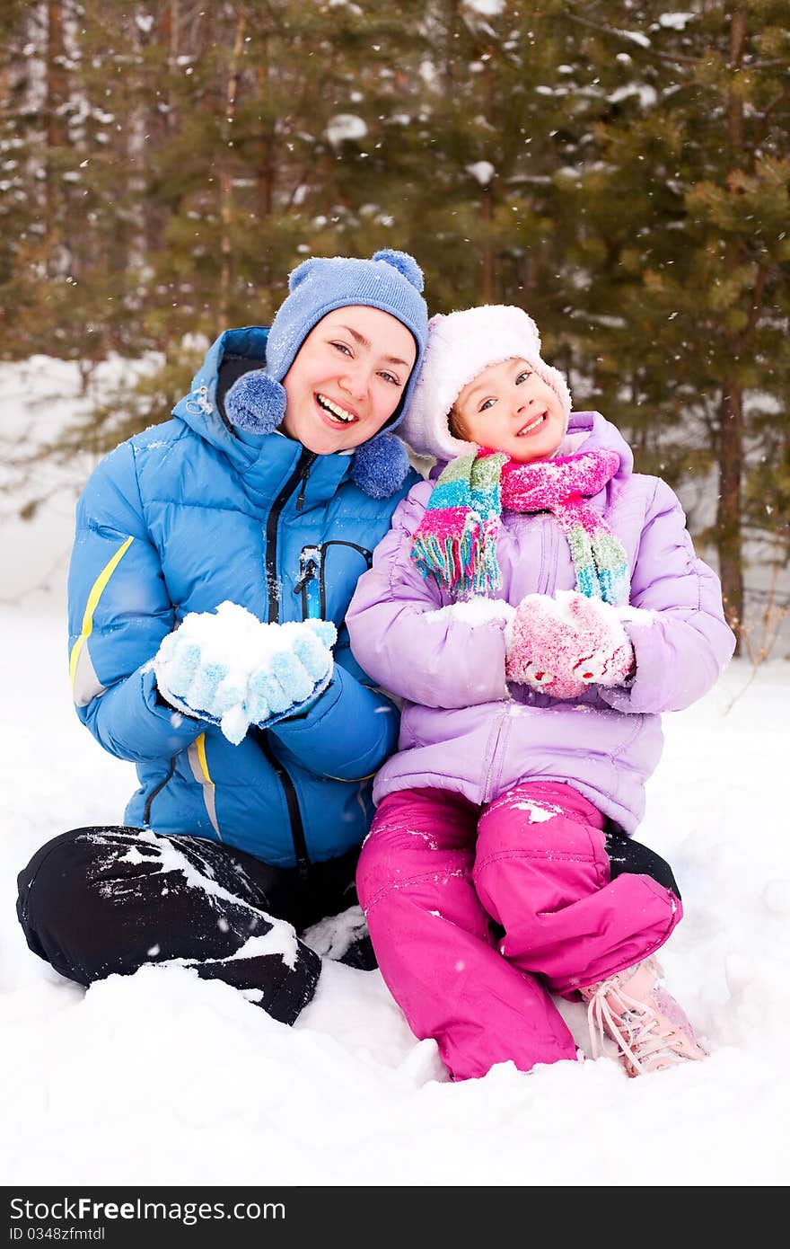 Happy family; young mother and her daughter having fun in the winter park (focus on the woman). Happy family; young mother and her daughter having fun in the winter park (focus on the woman)