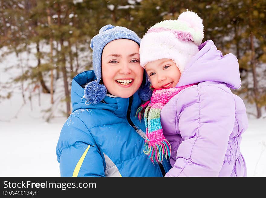 Happy family; young mother and her daughter having fun in the winter park (focus on the child). Happy family; young mother and her daughter having fun in the winter park (focus on the child)