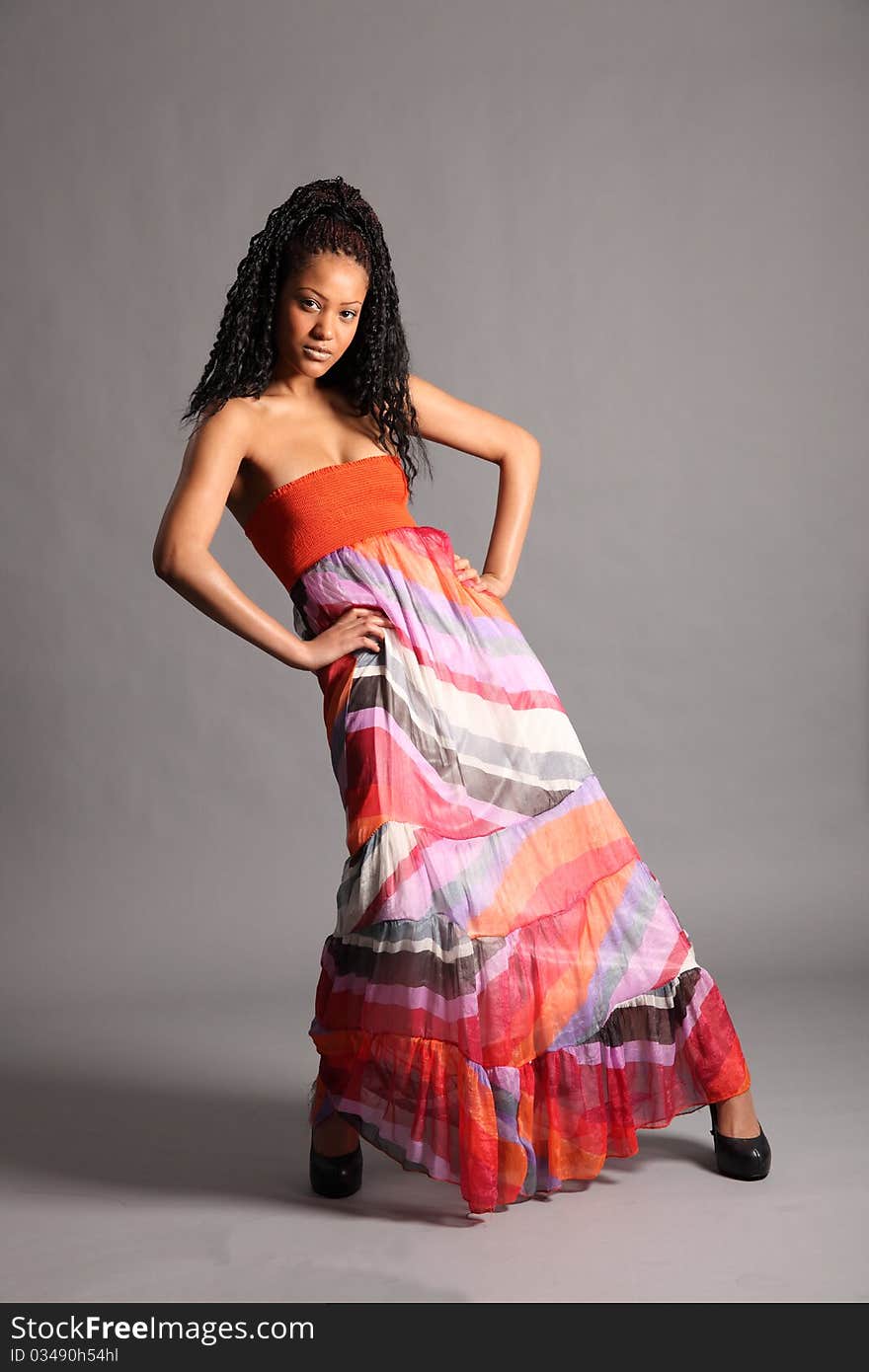 Beautiful young African girl wearing colourful dress. Studio shot, full length on grey backdrop. Beautiful young African girl wearing colourful dress. Studio shot, full length on grey backdrop.