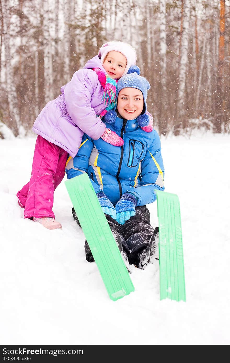Happy family; young mother and her daughter skiing and having fun in the winter park (focus on the mother). Happy family; young mother and her daughter skiing and having fun in the winter park (focus on the mother)