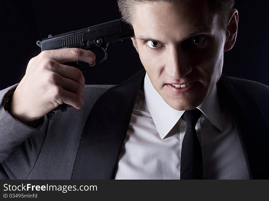 Young attractive macho in suit with gun