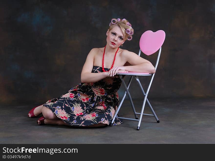 Photograph showing retro style 50s female relaxing next to stool with heart on. Photograph showing retro style 50s female relaxing next to stool with heart on