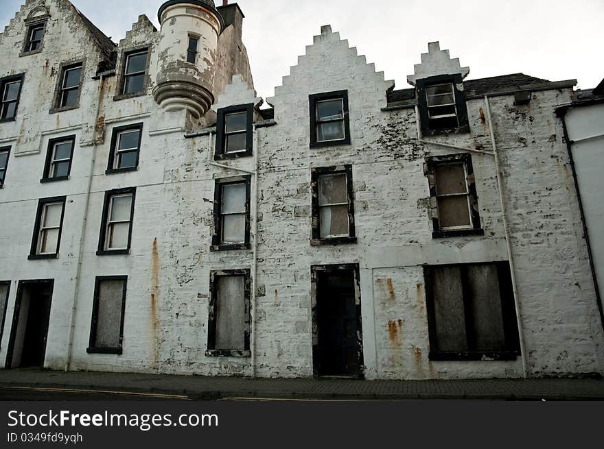 Abandoned historic building with windows boarded up and peeling paint, Scotland