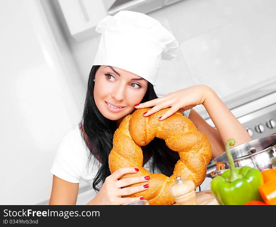 Beautiful cook with bread and vegetables in the kitchen at home