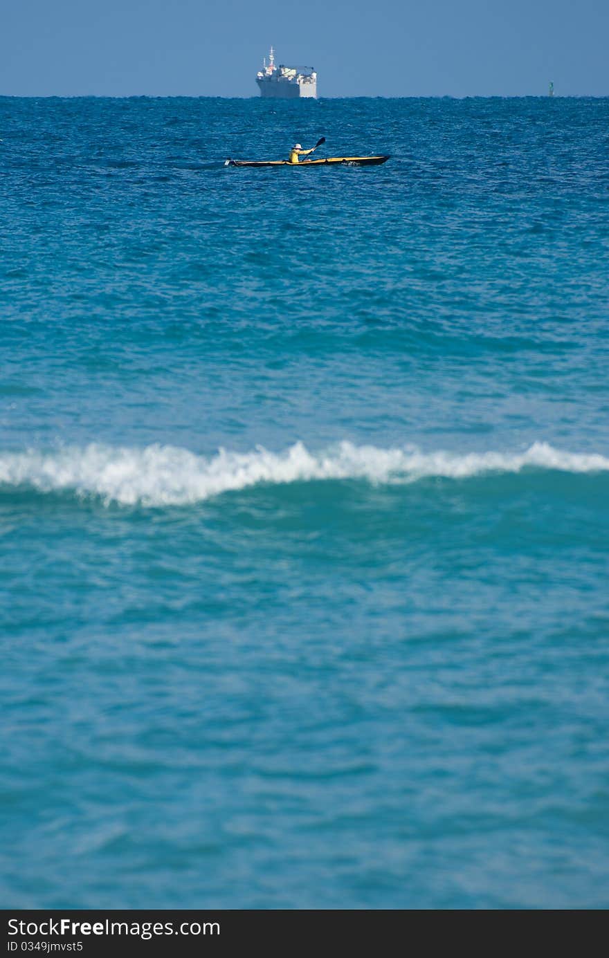 Kayaker at top third below a tanker on the horizon on the vast ocean. Kayaker at top third below a tanker on the horizon on the vast ocean.