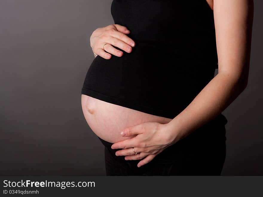 Beautiful pregnant woman staing on grey background