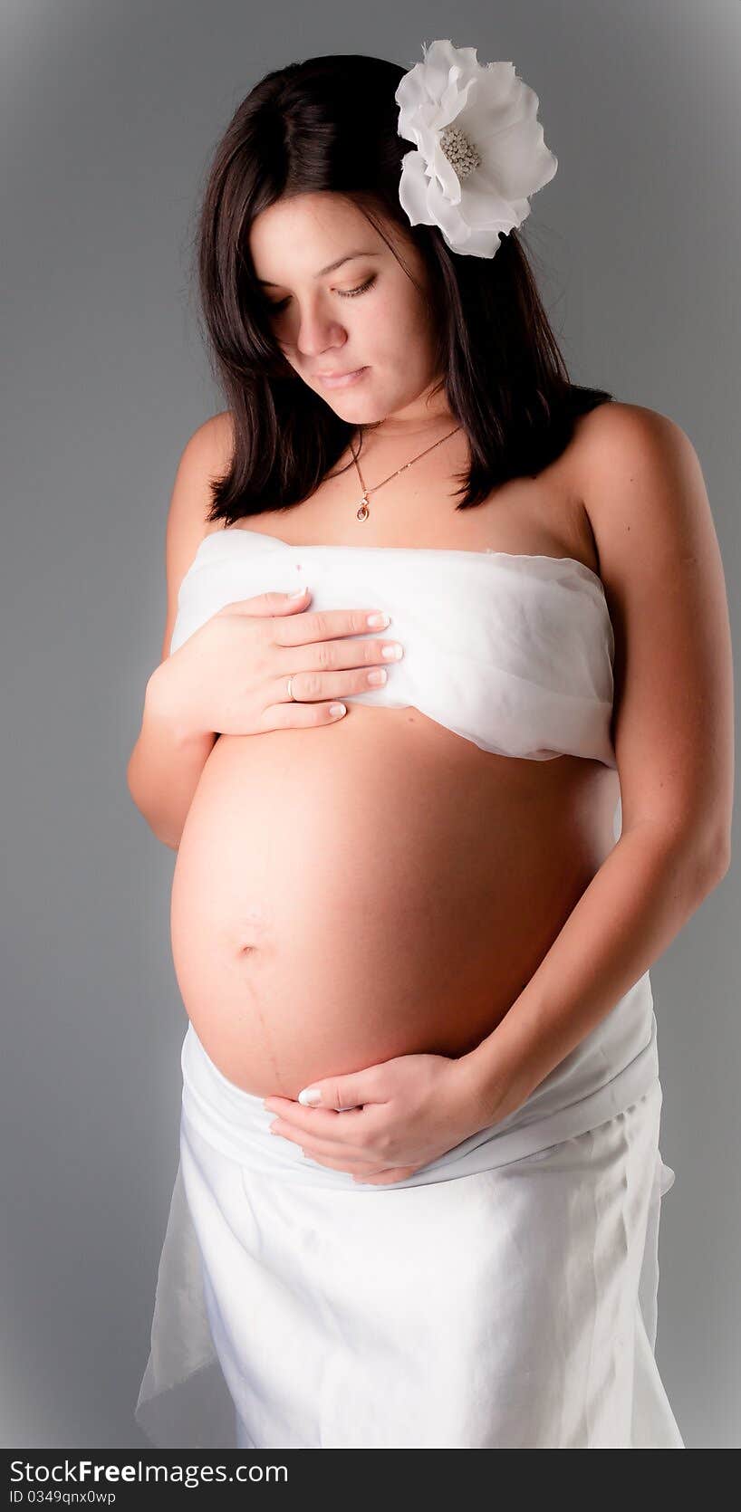 Beautiful pregnant woman staing on grey background, close up