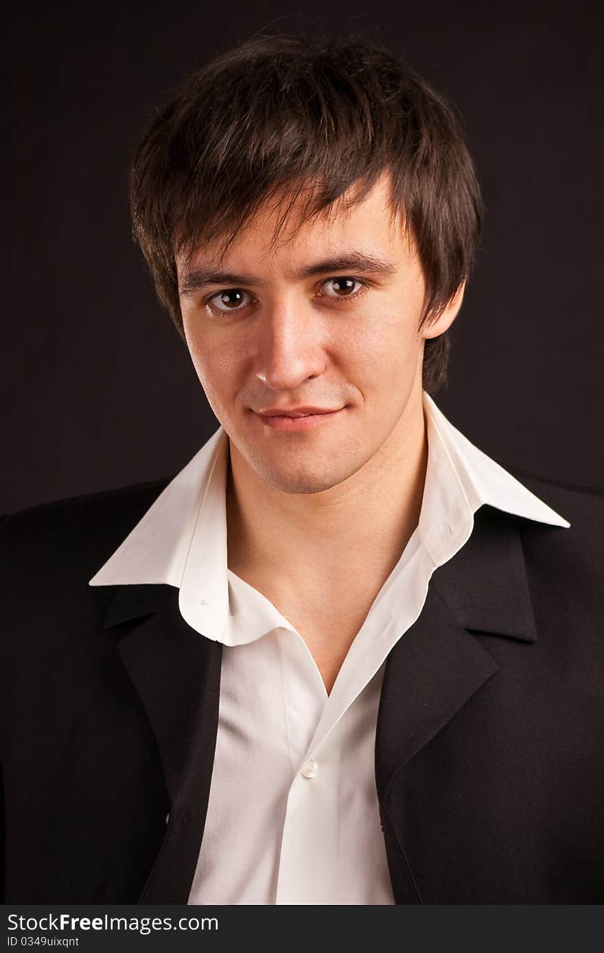 Portrait adult guy in a business suit on black backdrop