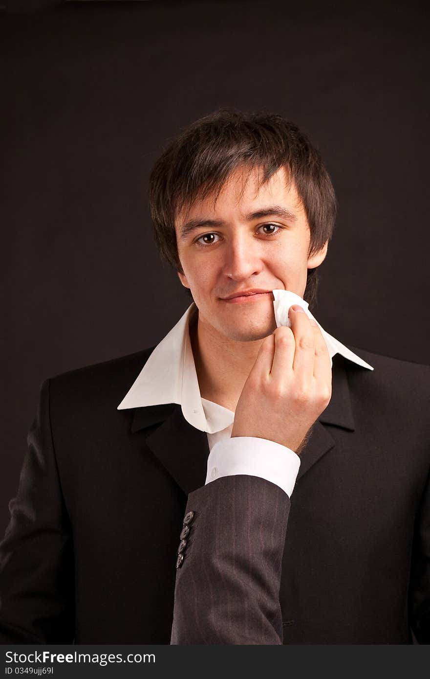 Businessman wipe a mouth on black backdrop