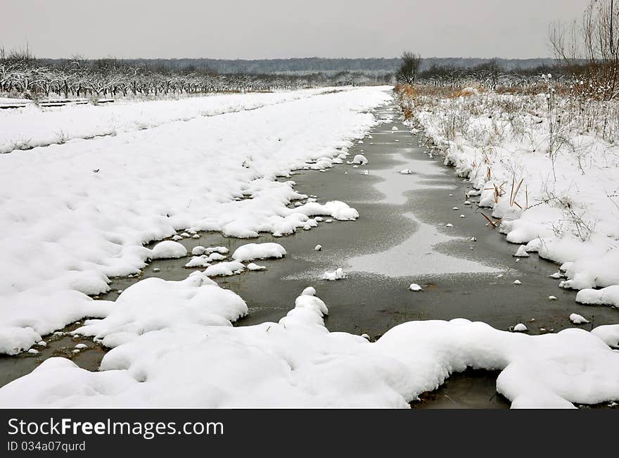 Frozen little river in winter filed