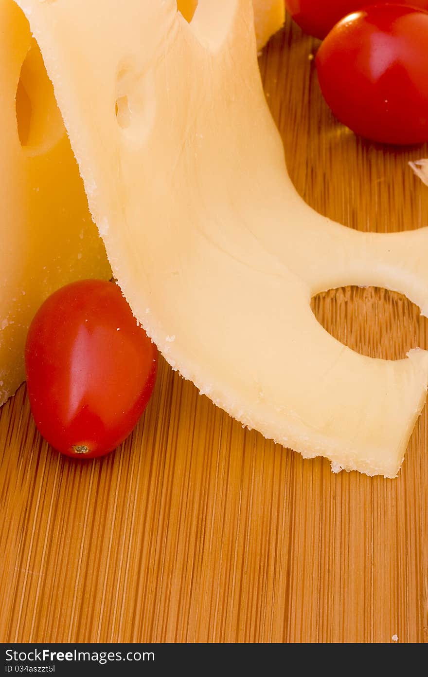 Swiss cheese slice and red tomato on a wood desk.