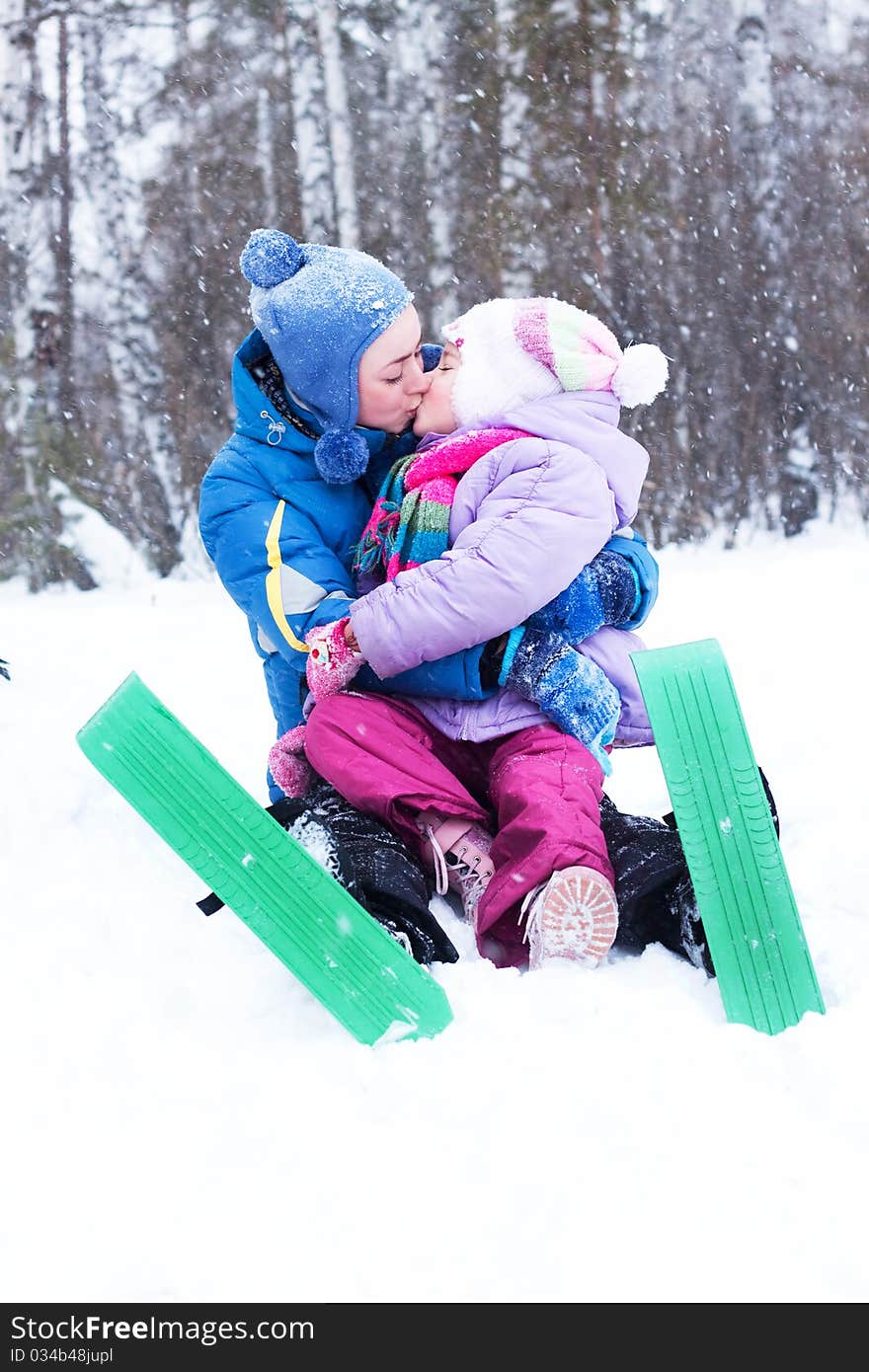 Happy mother and daughter, the family for a walk in a winter park, luge, skiing, skating, snowballs. Happy mother and daughter, the family for a walk in a winter park, luge, skiing, skating, snowballs