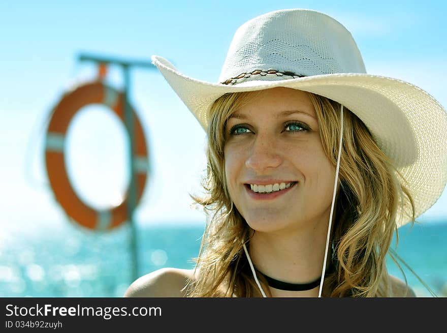 Young blond at the sea shore wearing hat