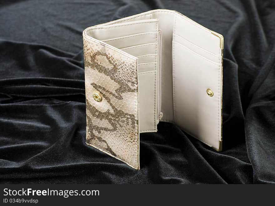 A horizontal image of a ladies snakeskin purse open and standing on black velvet