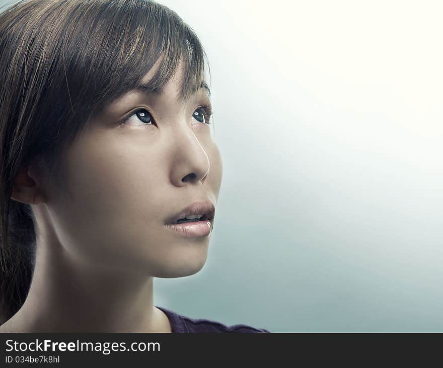 Studio photo of pretty young woman looking up