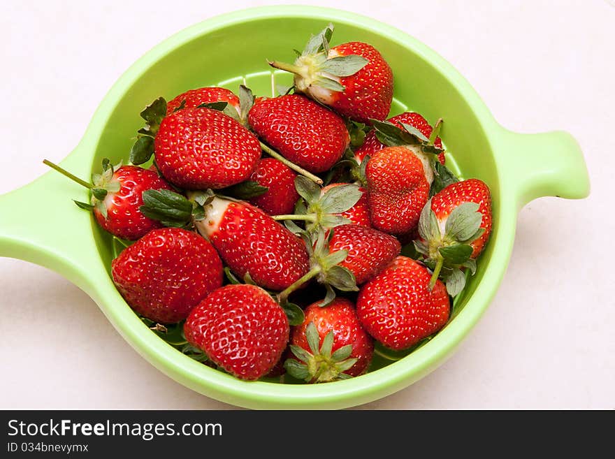 Ripe red strawberries in a green bowl