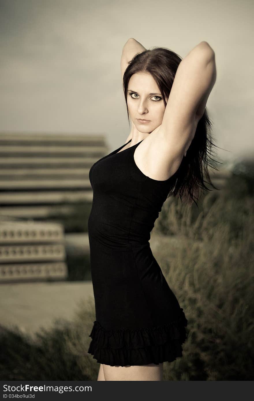 Woman in a black dress with the hands up against a background of construction