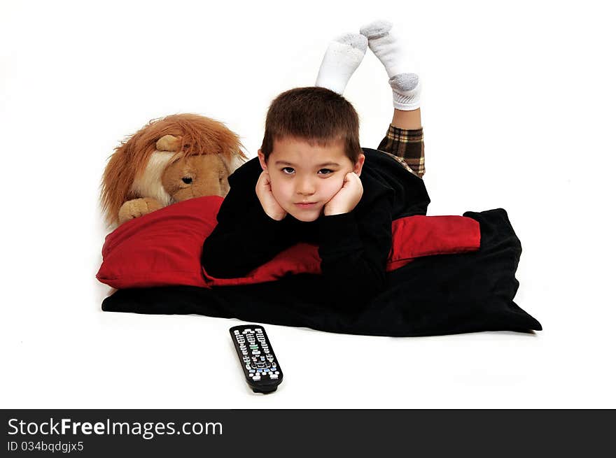 Young boy lounging on pillows on the floor propped up with hands, watching television. Young boy lounging on pillows on the floor propped up with hands, watching television