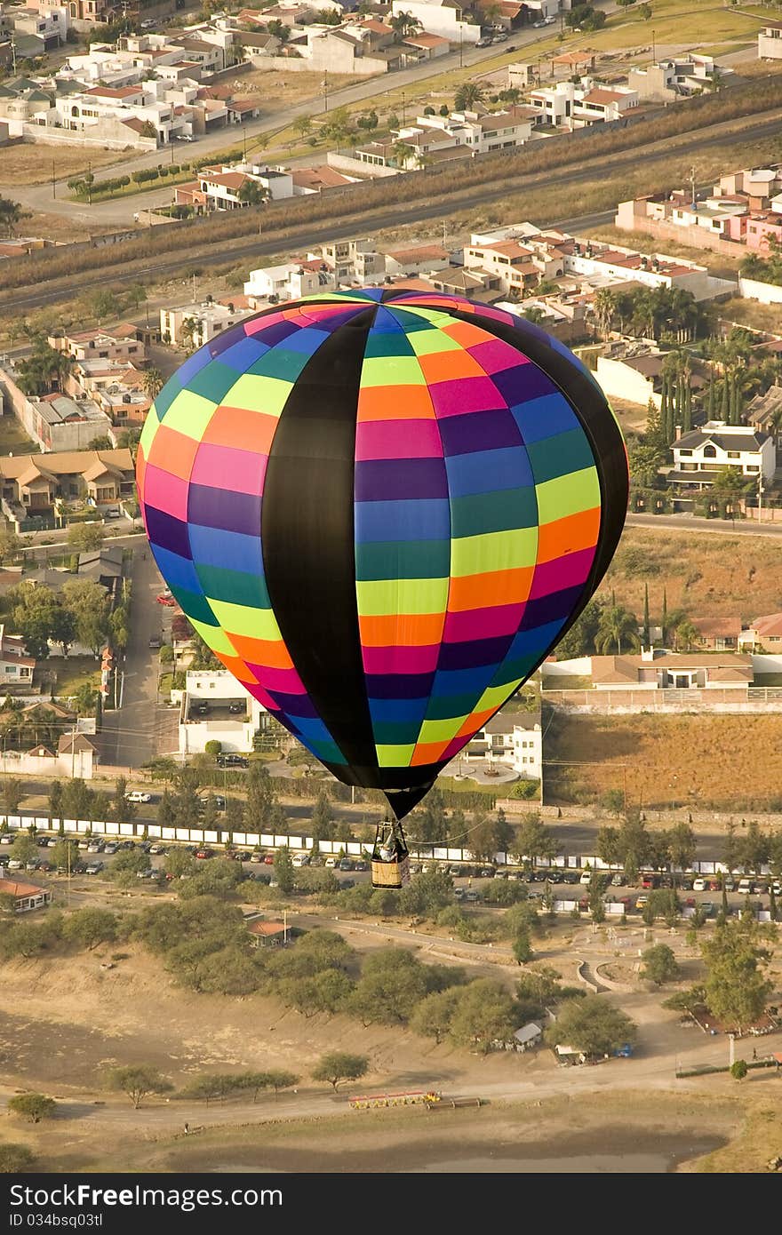 Multi color hot air balloon in flight with city in background