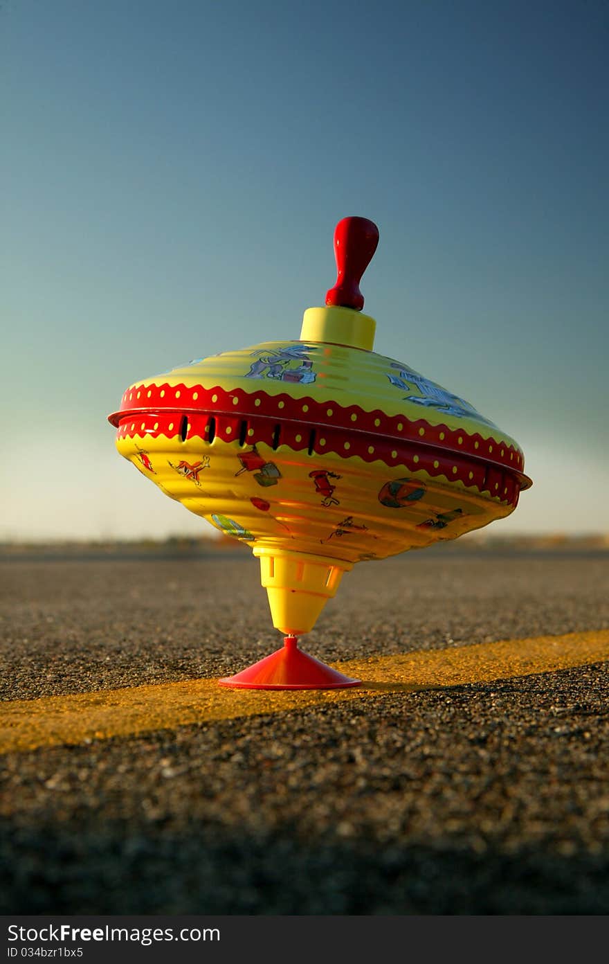 A late evening photo of a spinning plunger top in a parking lot with lots of bright colors. A late evening photo of a spinning plunger top in a parking lot with lots of bright colors.