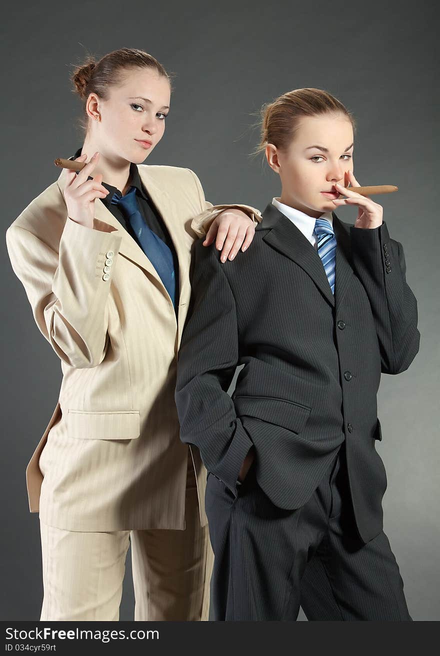 Two young girls with a cigar in man's suits. Two young girls with a cigar in man's suits