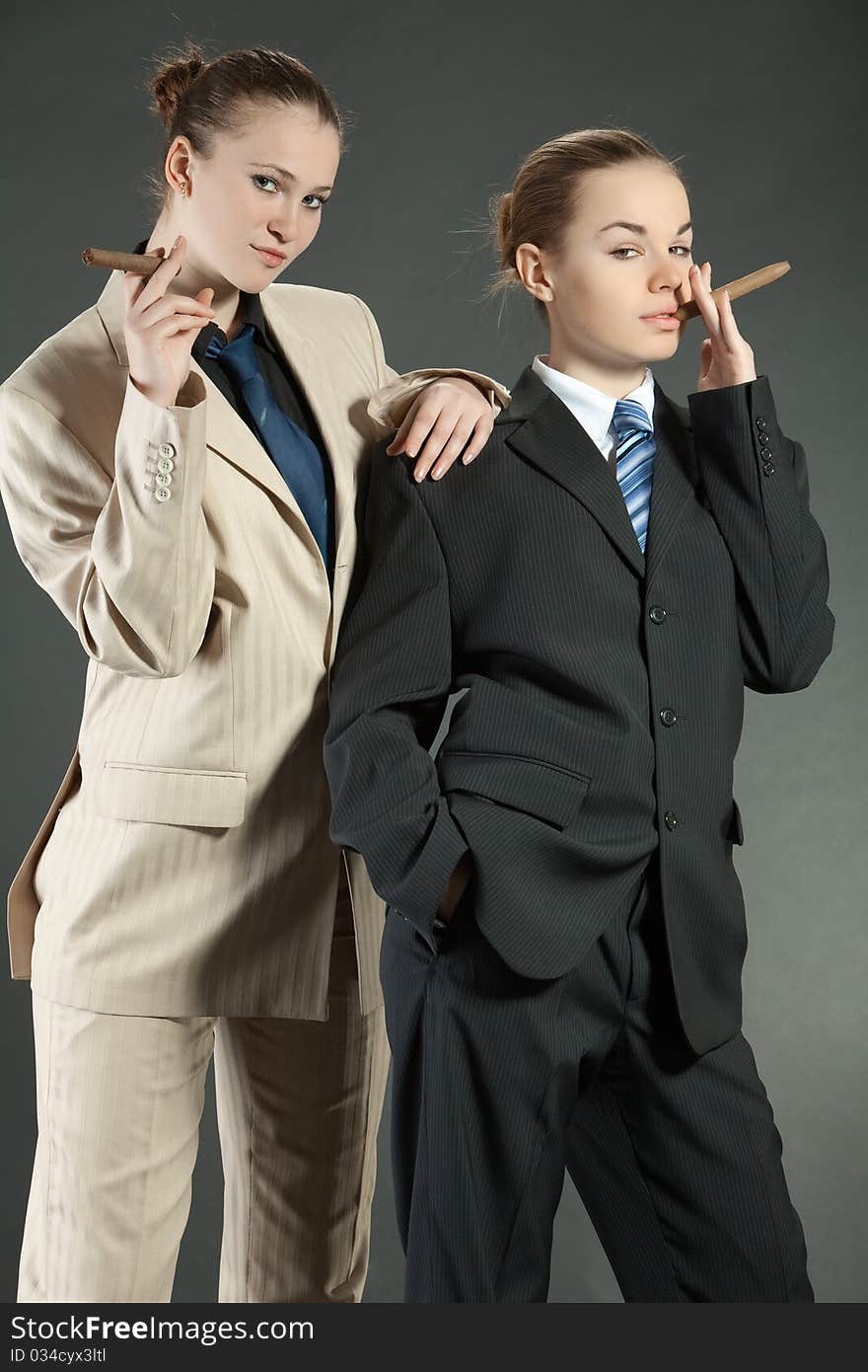 Two young girls with a cigar in man's suits. Two young girls with a cigar in man's suits