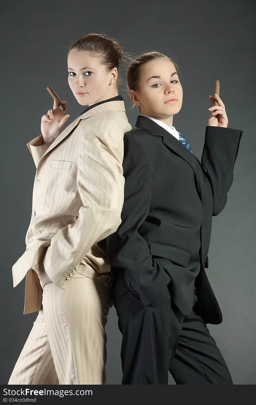 Two young girls with a cigar in man's suits. Two young girls with a cigar in man's suits