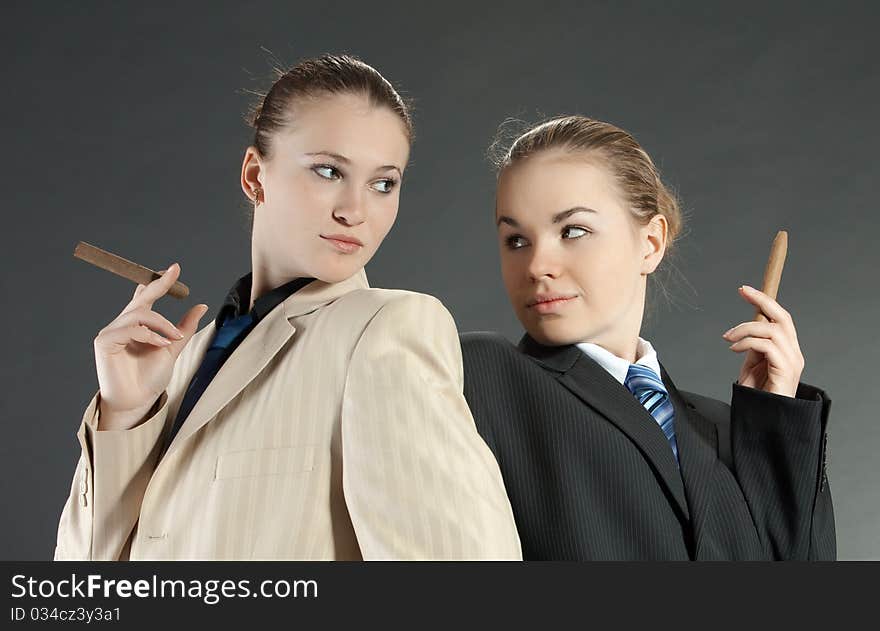 Two young girls with a cigar in man's suits. Two young girls with a cigar in man's suits