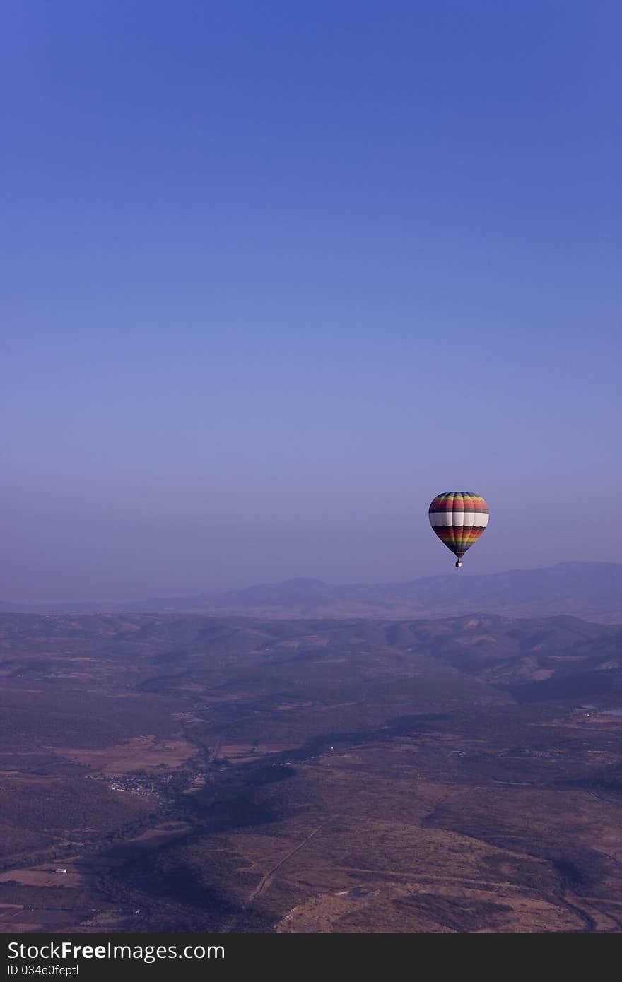 Single hot air balloon flying in mountains