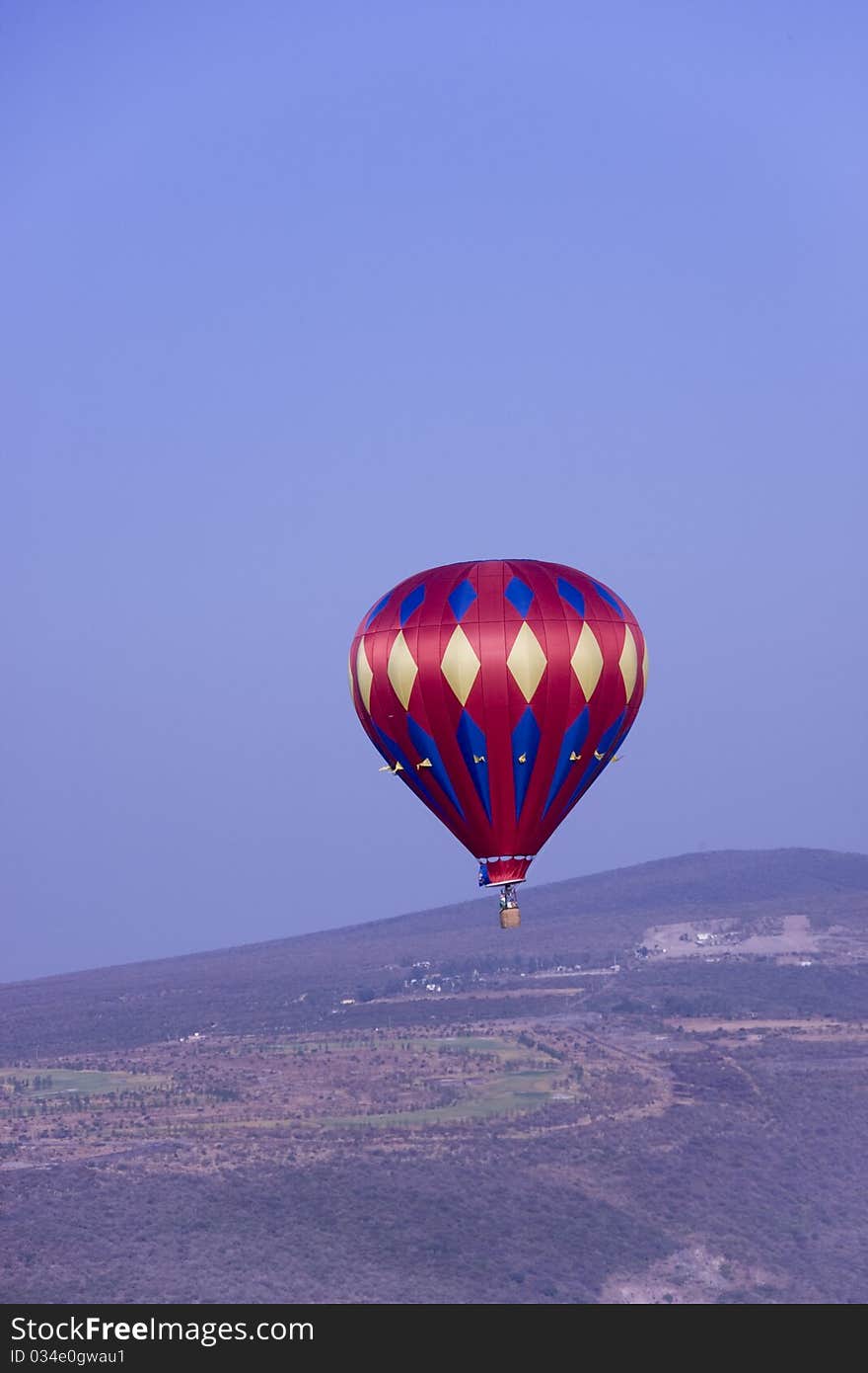 Verticle image of a red hot balloon flying in the mountains of central mexico. Verticle image of a red hot balloon flying in the mountains of central mexico