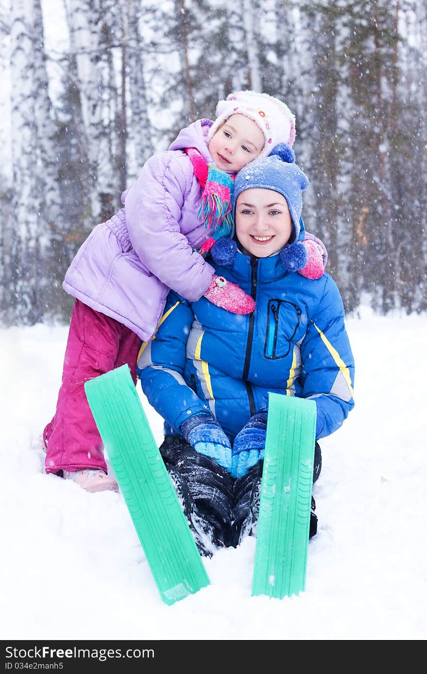 Happy mother and daughter, the family for a walk in a winter park, luge, skiing, skating, snowballs. Happy mother and daughter, the family for a walk in a winter park, luge, skiing, skating, snowballs