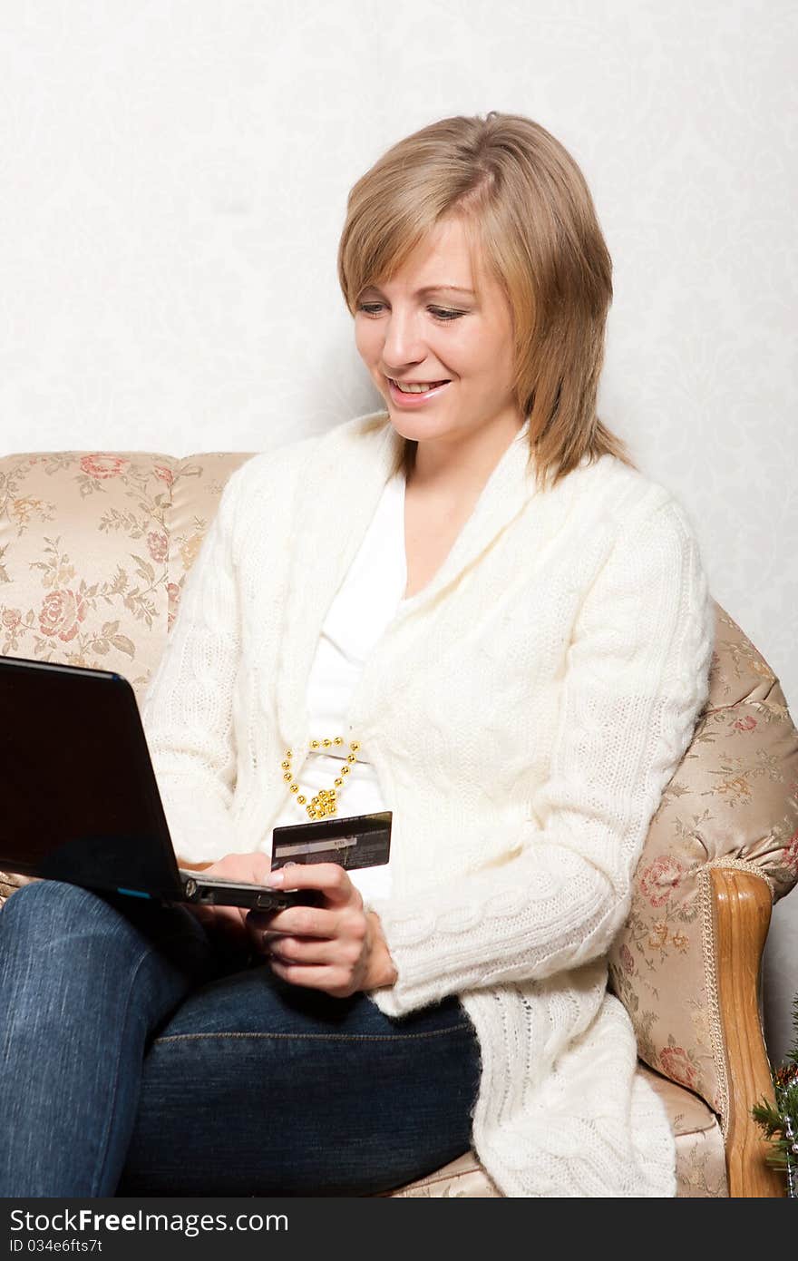 A young woman sits with a notebook on a soft sofa. A young woman sits with a notebook on a soft sofa