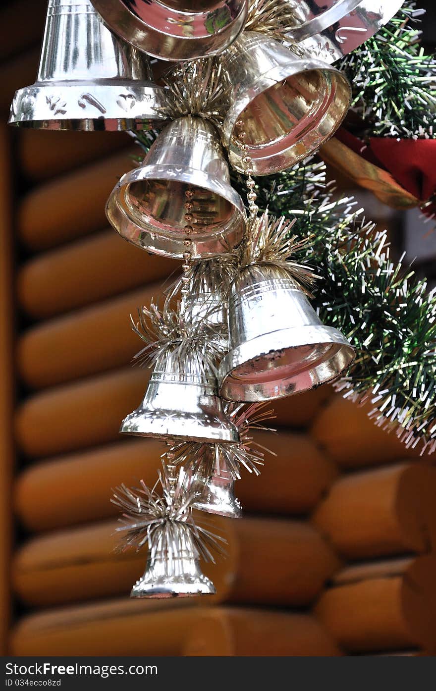 A decoration for Christmas composed by bell and pine braches, hanging on wooden house. A decoration for Christmas composed by bell and pine braches, hanging on wooden house.