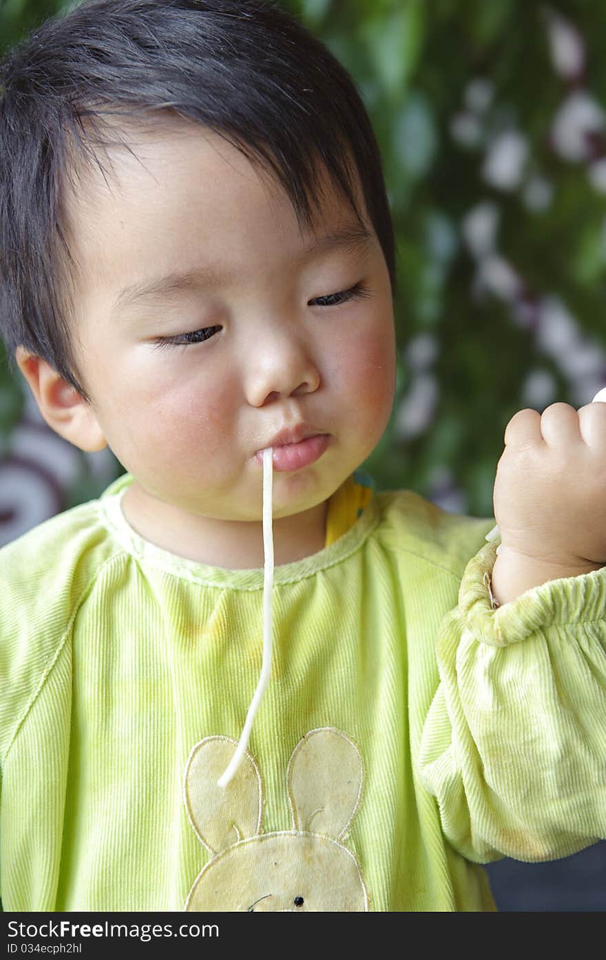 A cute baby is eating noodles